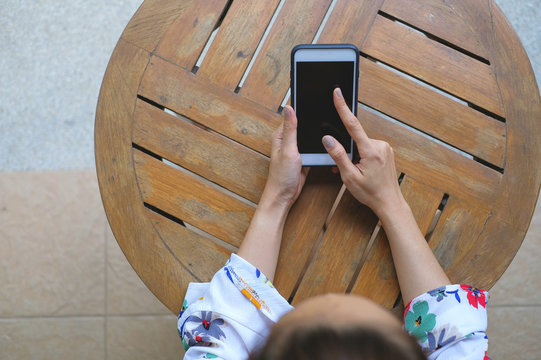 top view girl play mobile phone on table wood
