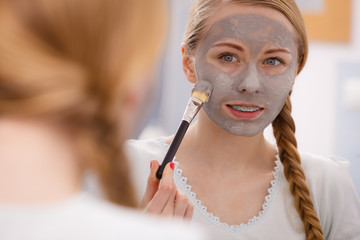 Woman with grey clay mud mask on her face