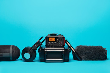 equipment for field audio recording on blue background. shotgun microphone, recorder,  windshield,...