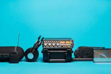 equipment for field audio recording on blue background. Windshield, shotgun microphone, radio system, boompole, portable case, mixer and headphones - 188539602