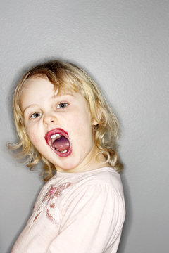 Portrait of little blonde girl with stained lips opening mouth
