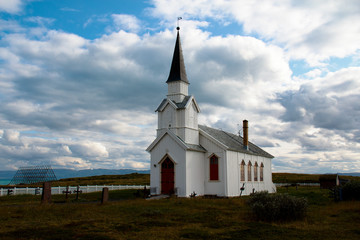 Fototapeta na wymiar White wooden church with graveyard in Finnmark