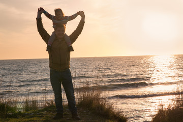 father with a baby girl at sunset by the sea