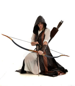 full length portrait of girl wearing brown  fantasy costume, holding a bow and arrow, on white studio background. 