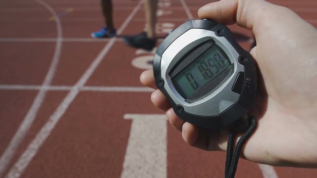 Hand of referee fixing time on stopwatch at running competition, sport challenge