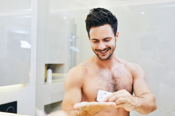 Attractive young man taking pills in the bathroom