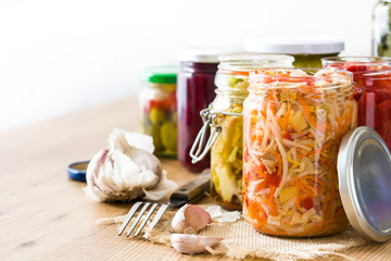 Fermented preserved vegetables in jar on wooden table. Copyspace