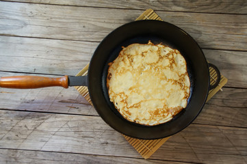 Red, delicious pancake in the pan on the wooden background. Delicious breakfast
