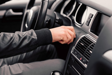 Businessman starts his stylish modern car with the key. Close up man's hand with the key.