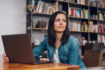 Thoughtful woman sitting working in a library