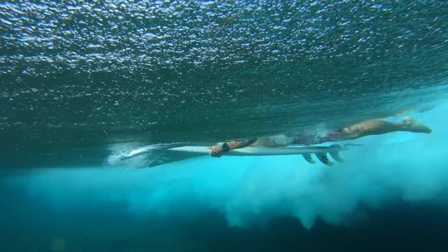 Surfer performs duck dive and passes the powerfull ocean wave. Underwater view of the rider