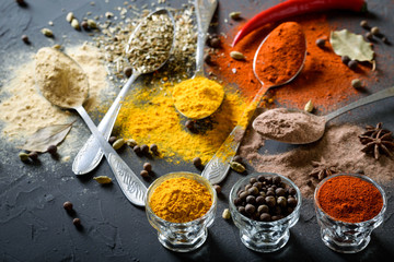 Various spices(pepper ground turmeric ginger cinnamon grass seasoning) in metal antique spoons on stone beton table. Top view