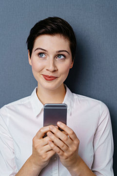 Thoughful smiling young woman using mobile phone