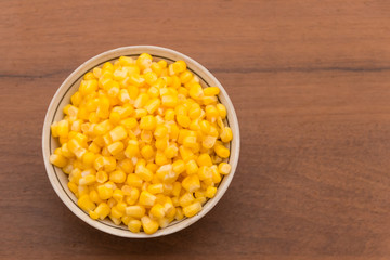 Canned sweet corn in a bowl on wooden table