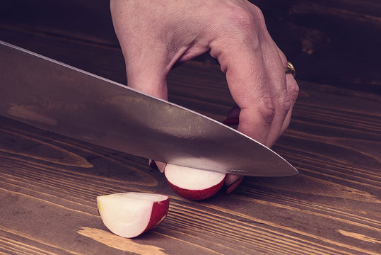 woman's hand cut radishes on a wooden board