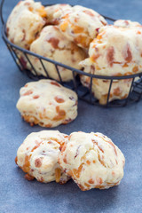 Homemade savory cookies with cheese and bacon in basket and on table, vertical