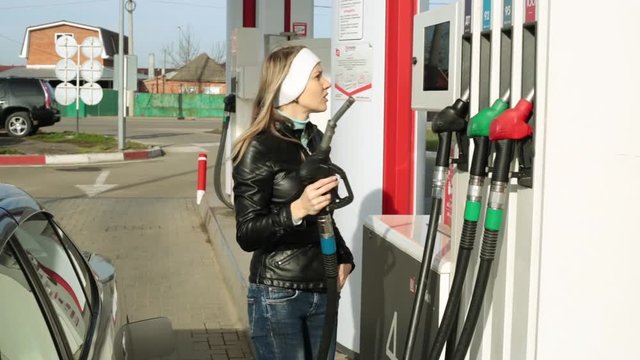 Woman driver at the gas station. A person pours gasoline into the car.