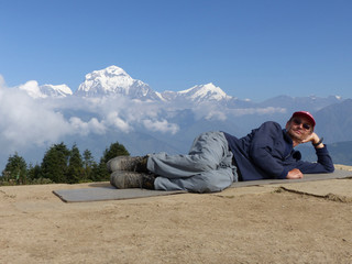 Happy hiker relaxing on Poon Hill, Dhaulagiri range on the backround - one of the most visited Himalayan view points in Nepal, view to snow capped Himalaya