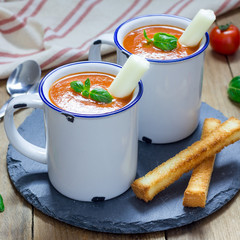 Homemade tomato basil soup in the mug, served with mozzarella cheese stick and croutons, square format