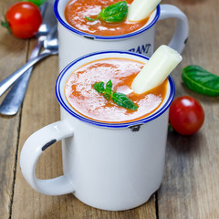 Homemade tomato basil soup in the mug, served with mozzarella cheese stick and croutons, square format