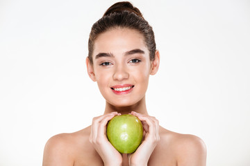 Photo of gorgeous woman with brown hair in bun holding big green apple in both hands like heart shape isolated on white background