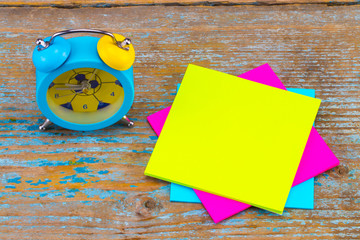  alarm clock and a  sticky notes with empty space for a text on wooden background
