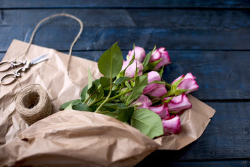 A bouquet of pink roses in brown paper. Color pastry macaroni. Free space for text or postcards.
