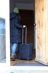Frau mit Gepäck an der Haustür