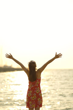 Girl standing a two hand up relax and freedom in the sea with sunset light