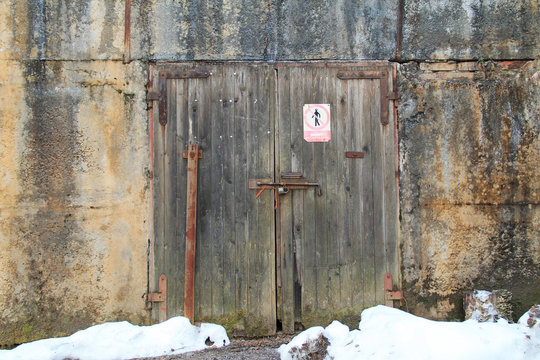 old wooden door of abandoned industrial building closed with a bolt
