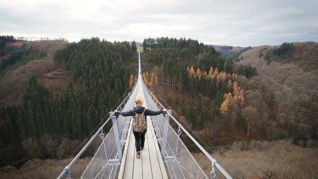 woman walking over hanging rope bridge in germany. wanderlust concept