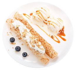 Serving pancakes with ice cream, nuts, blueberry and whipped cream on the plate. Decorated with caramel syrup. Isolated on white background. Top view.