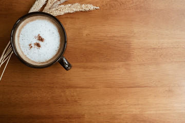 hot cappuccino coffee with cinnamon powder in black cup on wood table