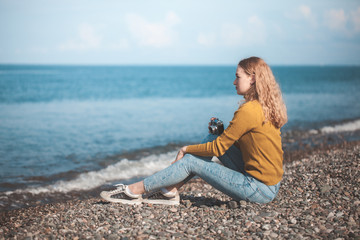 beautiful blonde girl on a sea beach with a old camera in hand