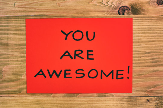 Message you are awesome on red paper  on wooden table.