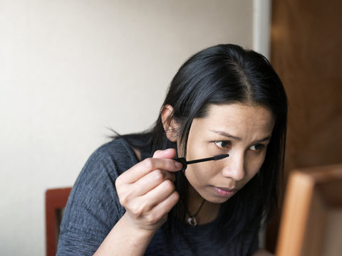 Woman painting eyelashes with mascara