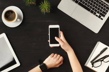 Woman's hands holding smartphone, top view
