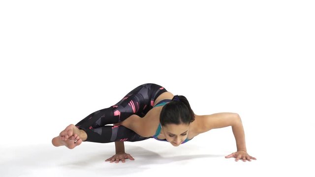 Young attractive woman practicing yoga doing Ashtavakrasana, Eight angled Pose in full length, isolated over white studio background