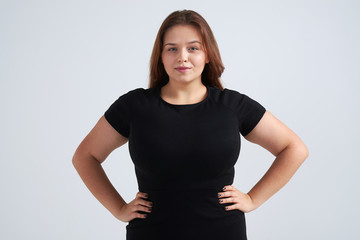 Pretty girl holding hands on waist while posing at camera