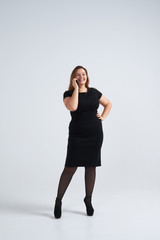 Happy young businesswoman in smart office dress talking on phone