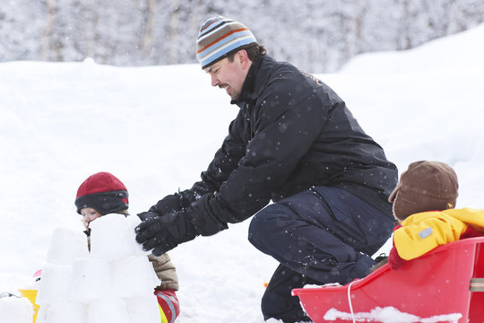 Father playing in snow with two little children