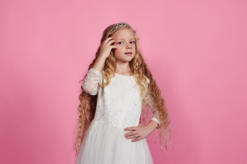 Obraz na płótnie Canvas Blonde little girl posing in white dress and diadem
