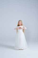 Fototapeta na wymiar Girl in white dress and diadem making heart shape