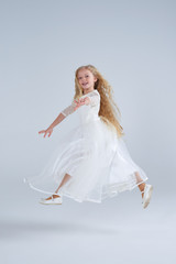 Fototapeta na wymiar Beautiful tender blond girl in white dress jumping