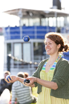 Young woman juggling balls outdoors