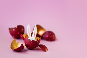 Easter concept. Colored eggs on pink background, Easter Bunny hiding inside