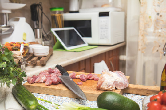Fresh meat and knife on cutting board in the kitchen table.Small cozy kitchen with household appliances. Cozy home concept