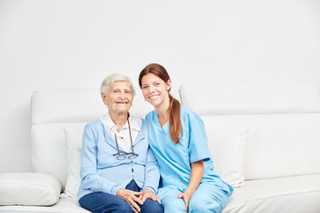 Seniorin und weiblicher Altenpfleger auf dem Sofa
