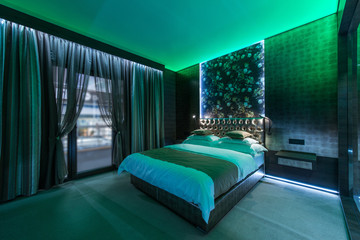 Green lights in luxury bedroom with double bed