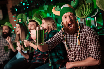 A man in a funny hat celebrates St. Patrick's Day with friends.